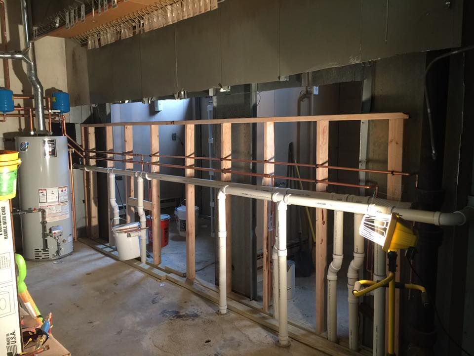 A room with a lot of pipes and water heaters in it.