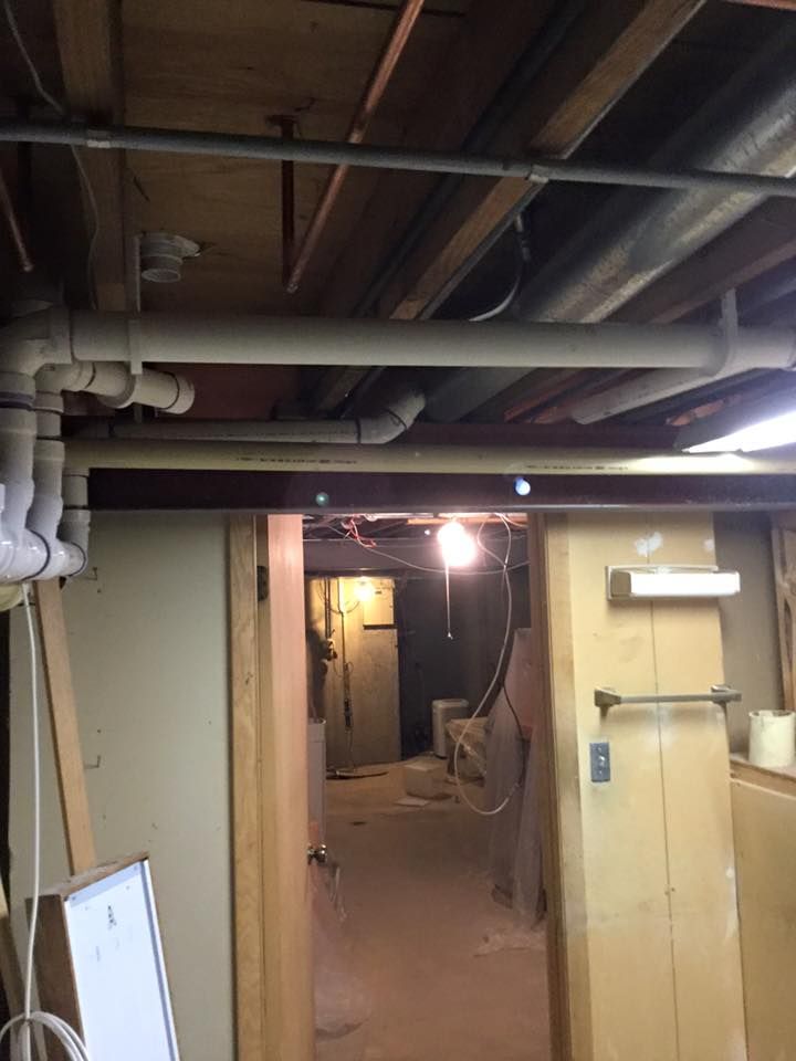 A basement with a lot of pipes hanging from the ceiling.