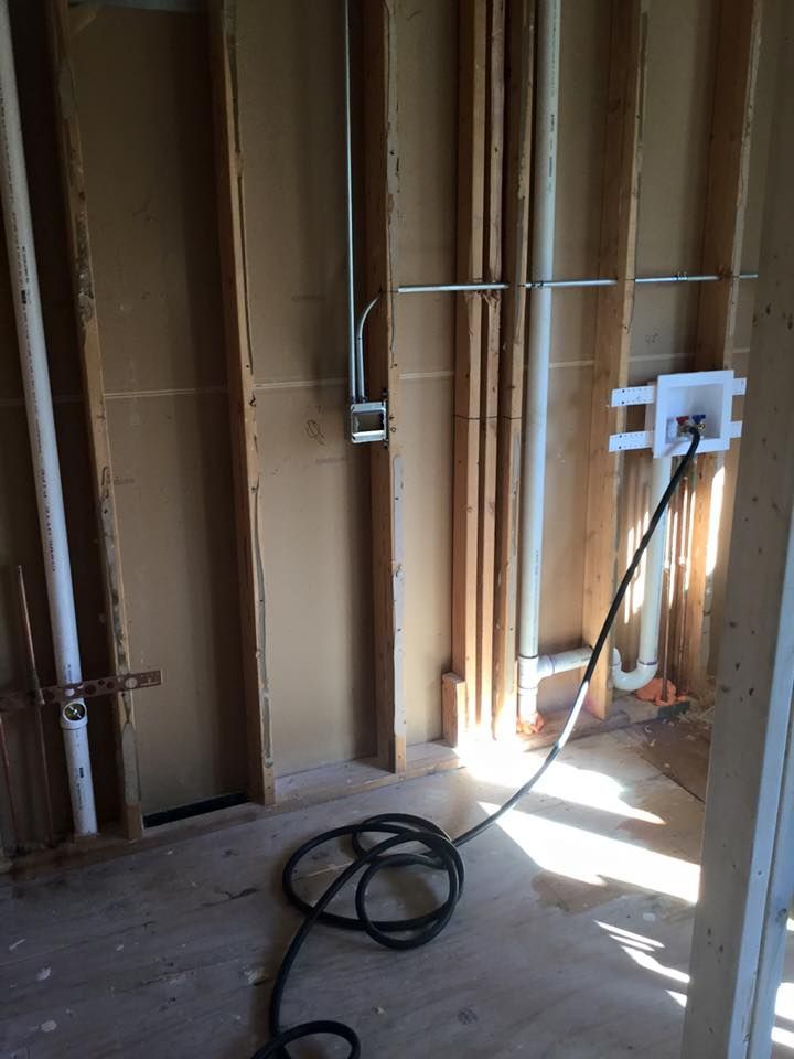 A vacuum cleaner is sitting on the floor in a room with pipes.