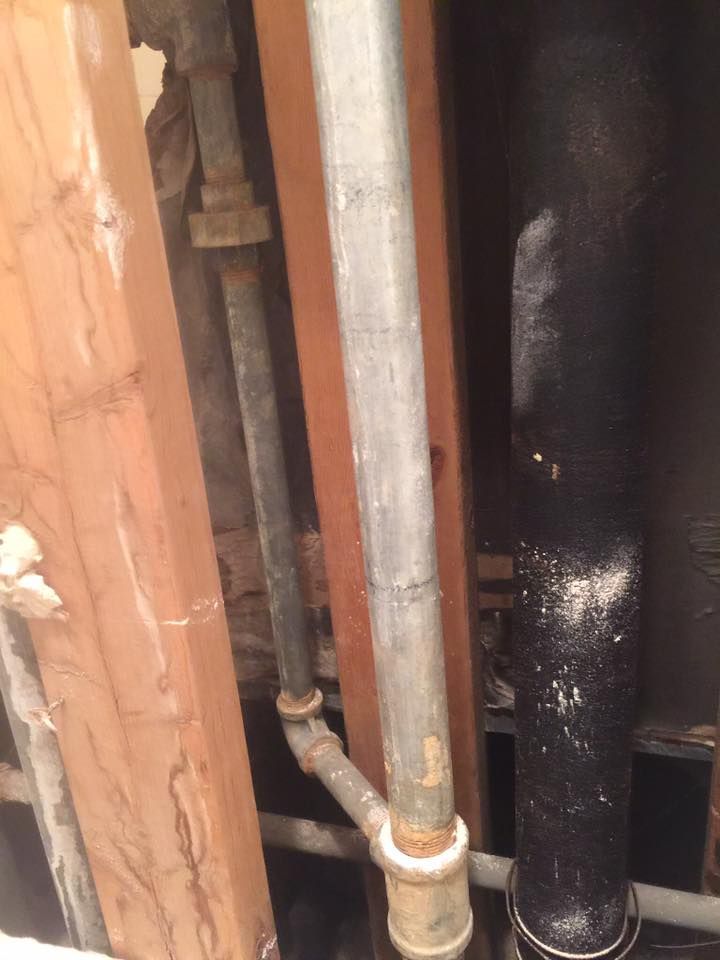 A bunch of pipes are hanging from a wooden wall.