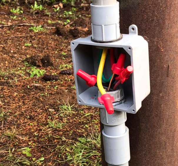 Electrical junction box with wires and connectors on a pole.
