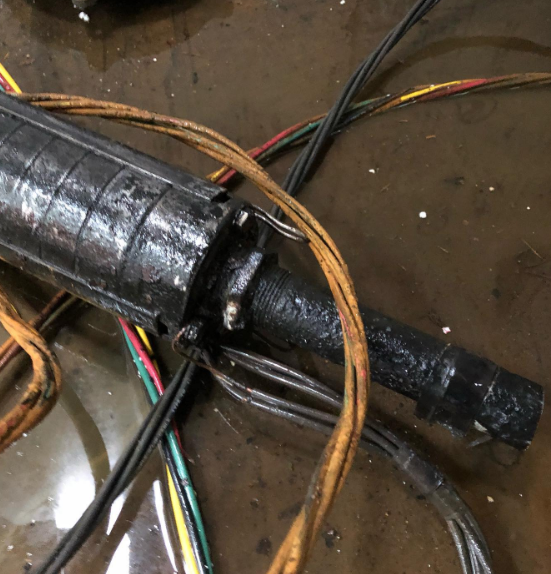Submersible well pump with wires partially submerged in water.
