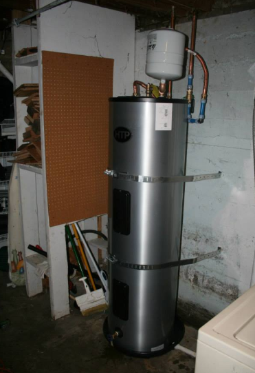 Silver water heater in a utility room, beside a pegboard and a white appliance.