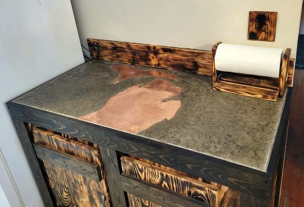 A wooden counter top with a paper towel holder on it.