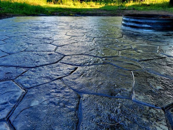A close up of a concrete patio with a manhole cover in the background.