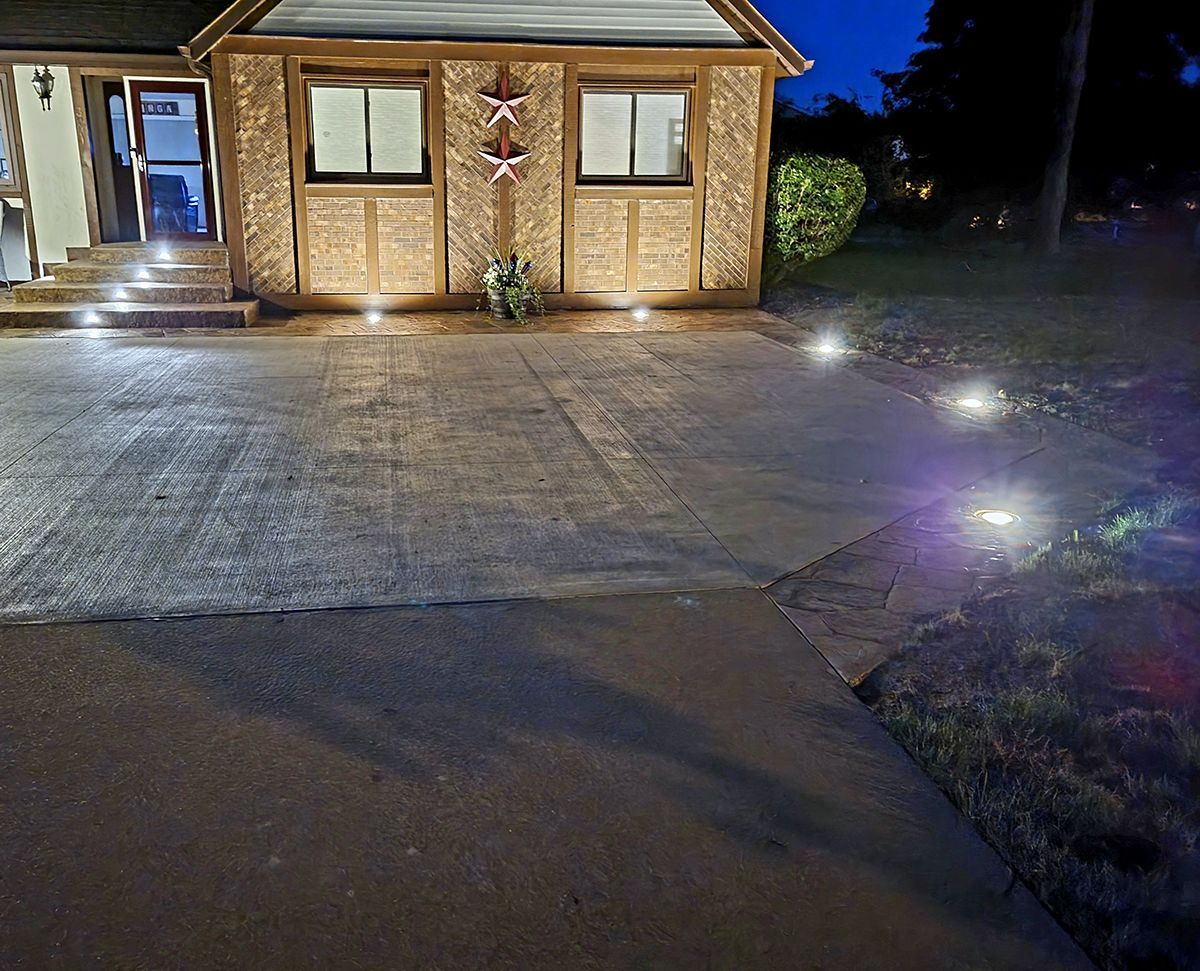 A house is lit up at night with a driveway in front of it.
