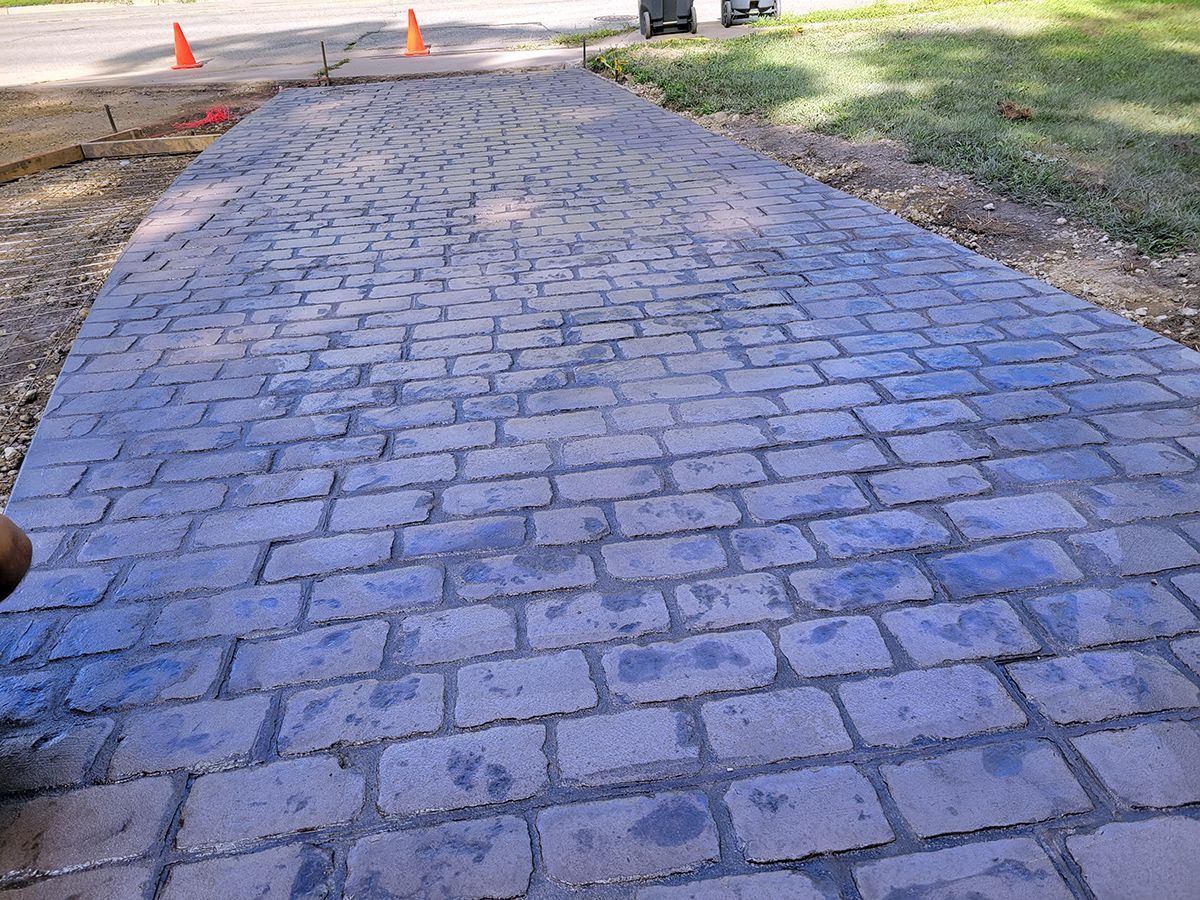 A person is standing on a brick walkway next to a road.