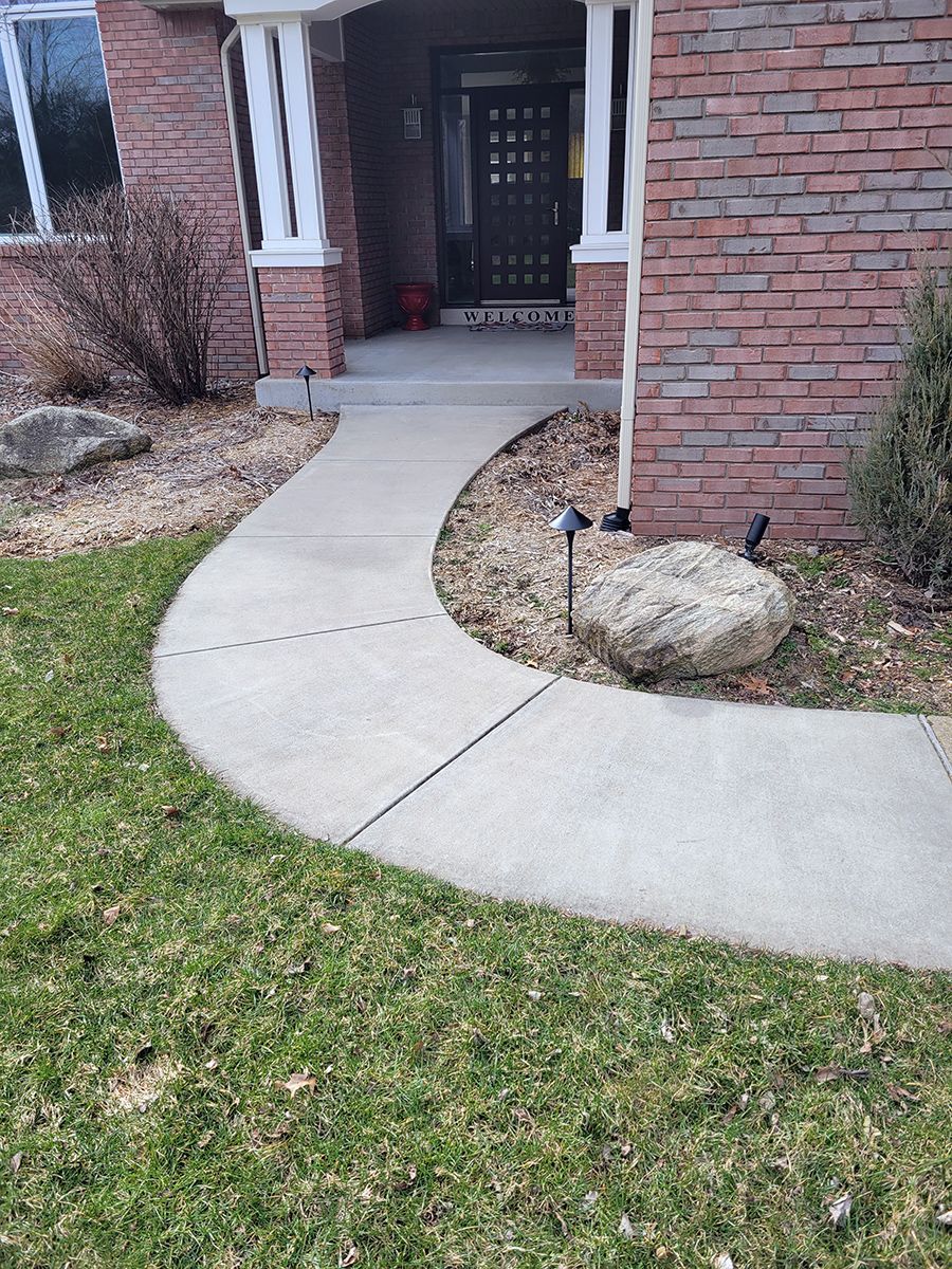 A brick house with a concrete walkway leading to the front door.