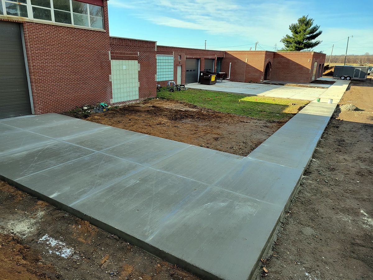 A concrete walkway is being built in front of a brick building