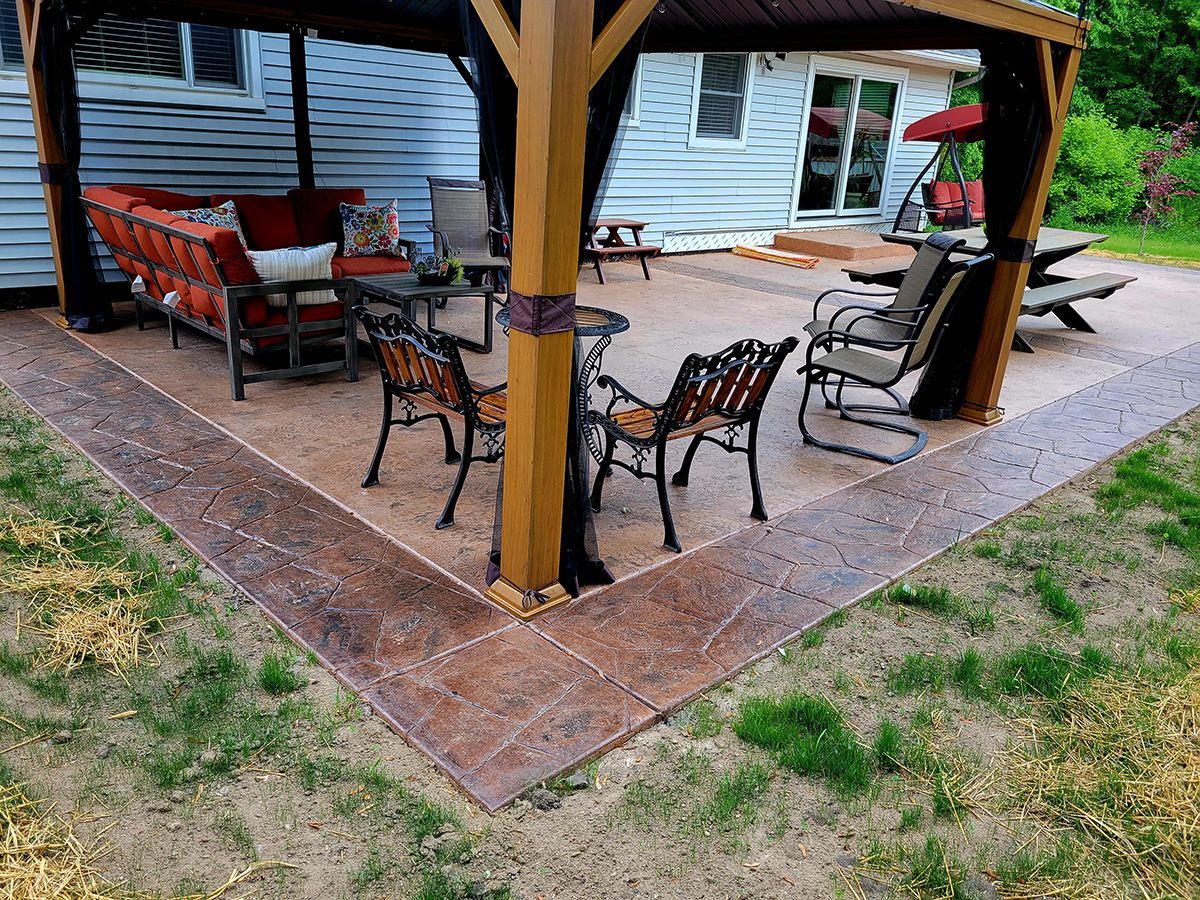 A patio with a gazebo and a couch and chairs underneath it.