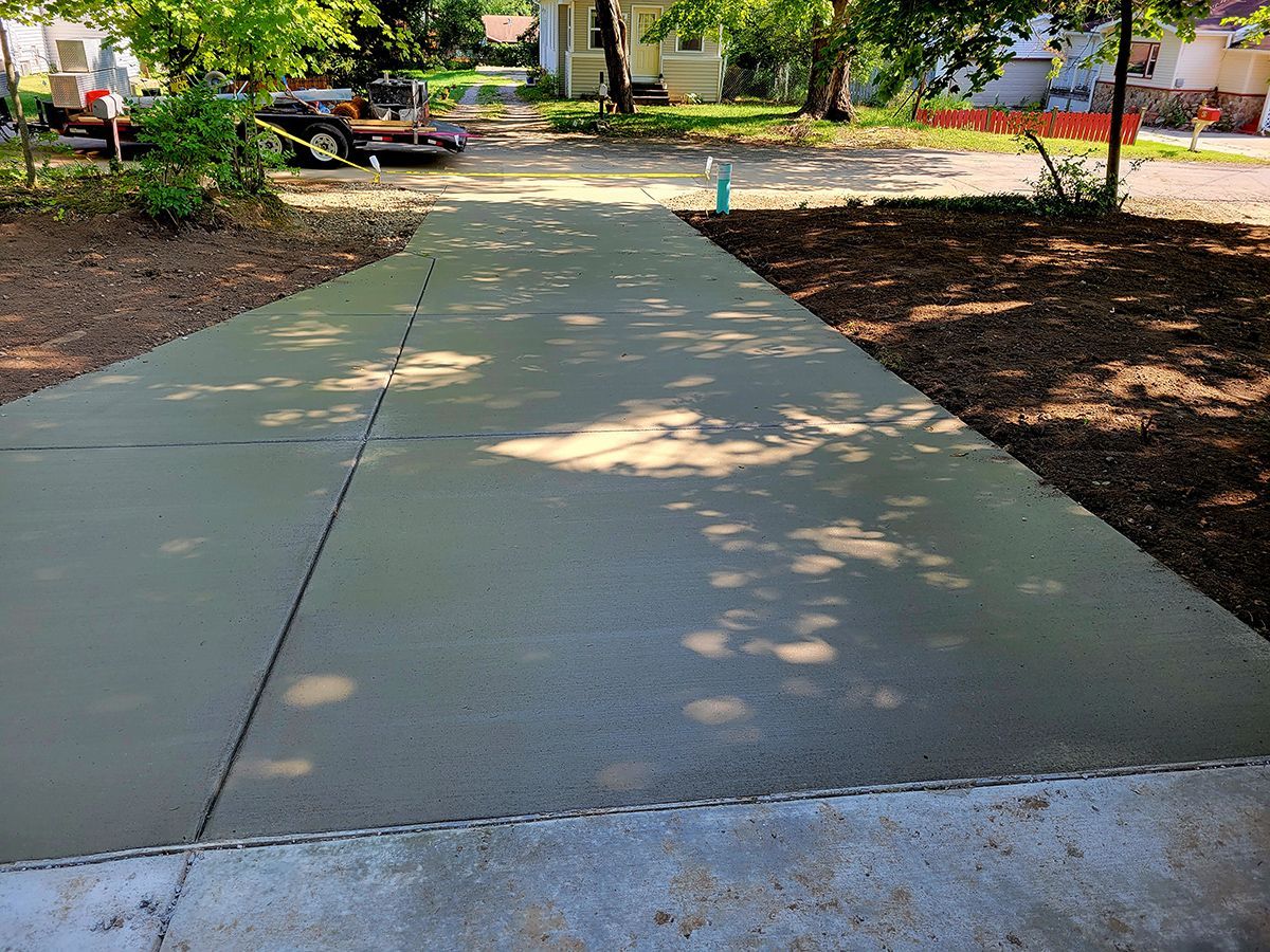 A concrete driveway with a car parked on the side of it.