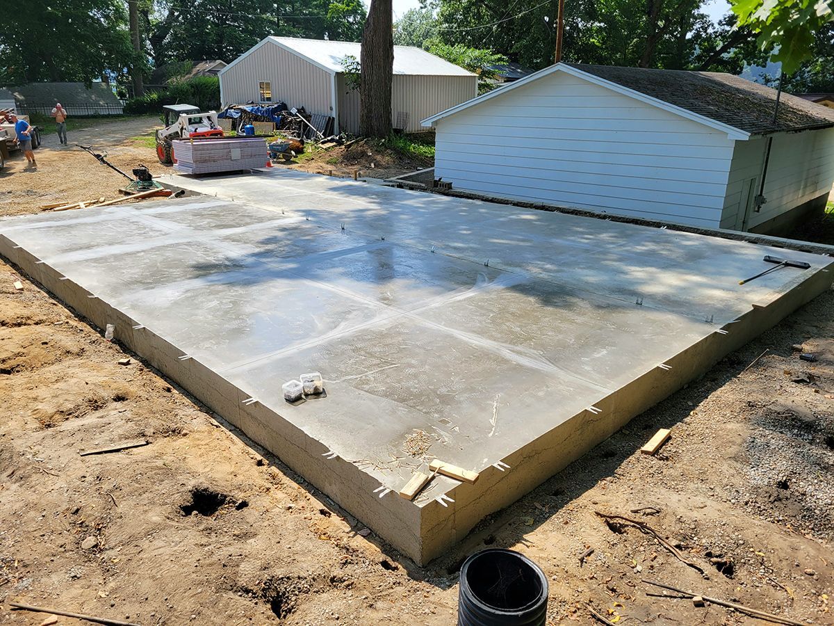 A concrete foundation is being built in front of a house.