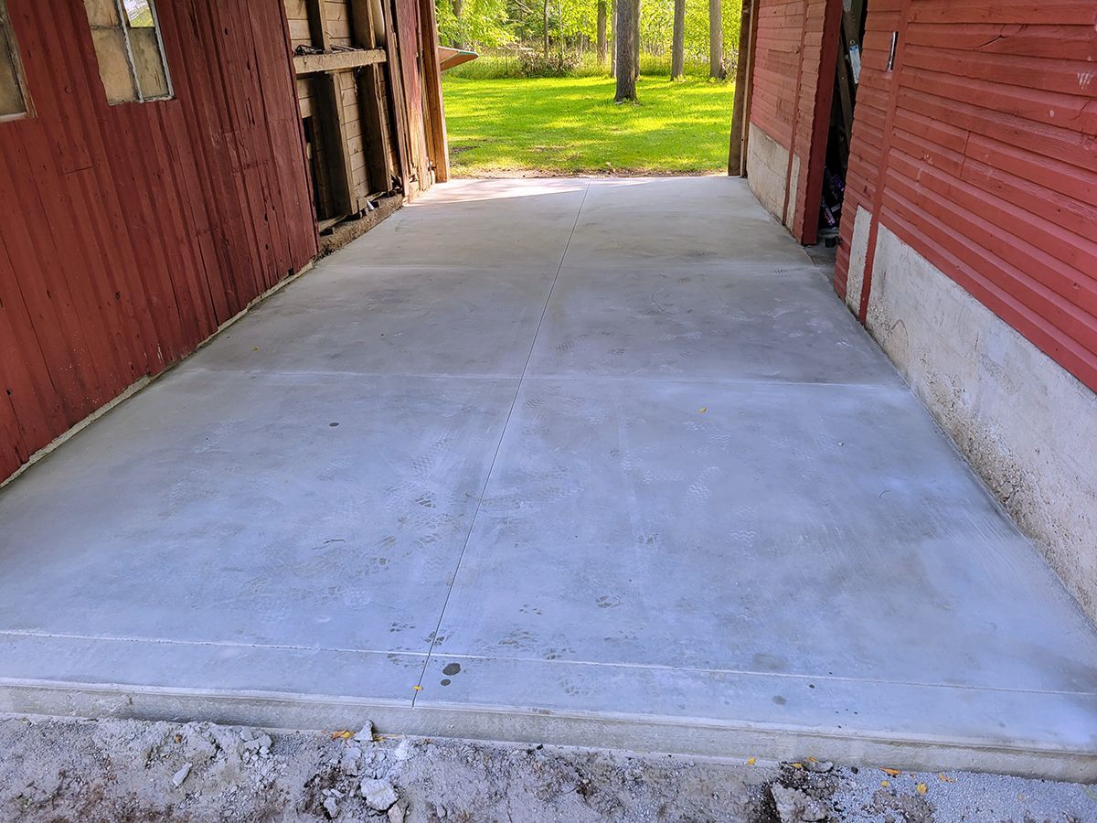 A concrete driveway in front of a red building.