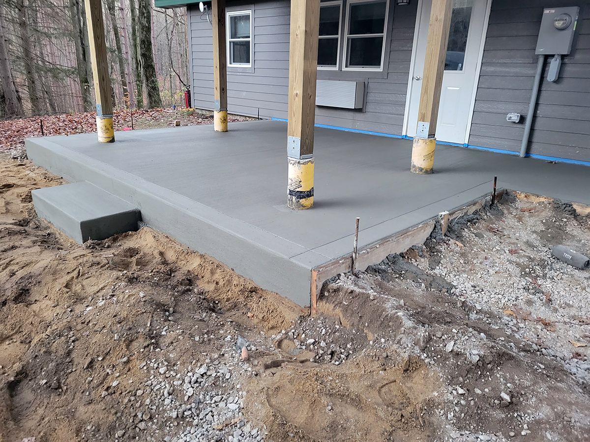 A concrete porch is being built in front of a house.