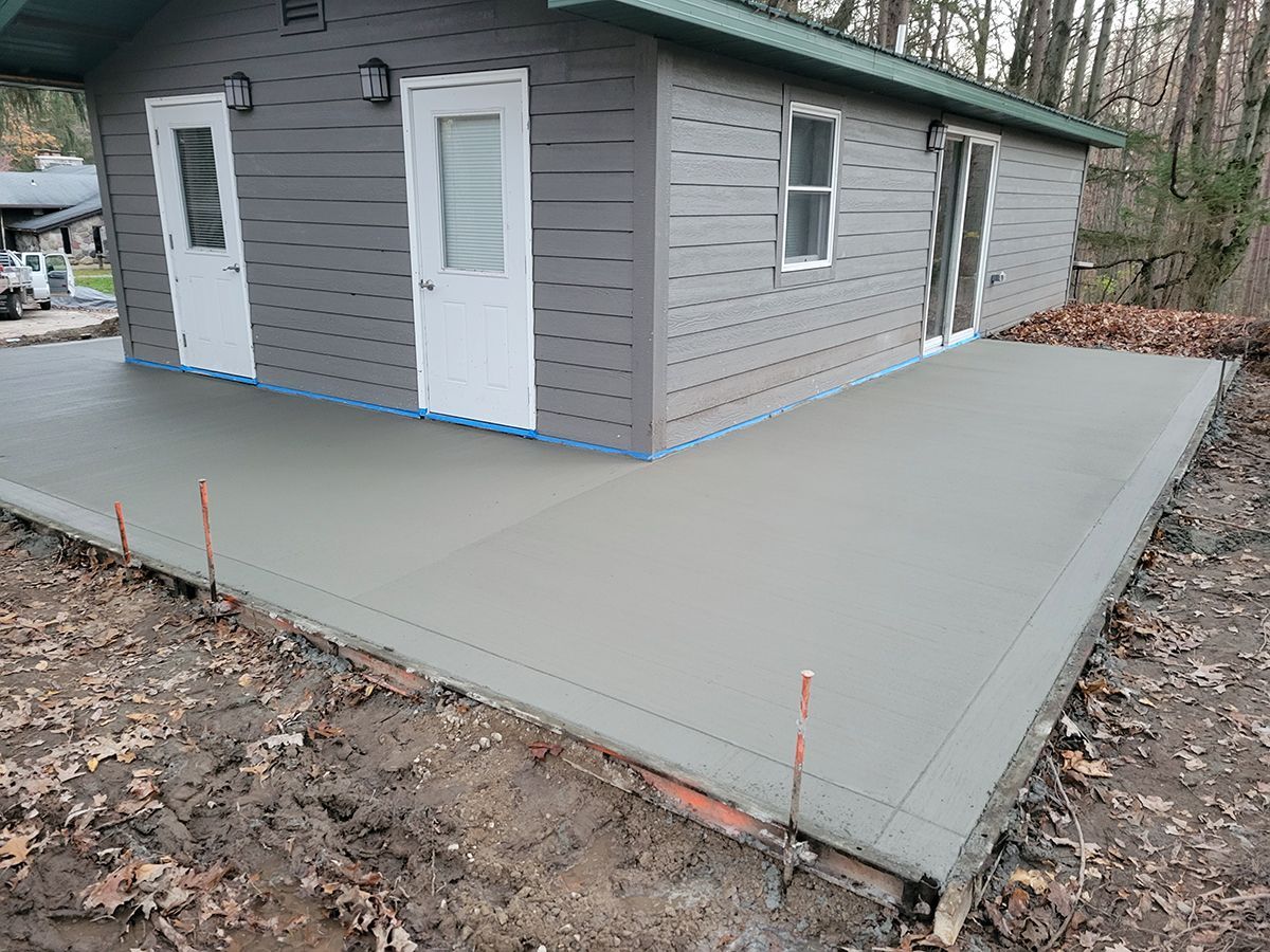 A small house with a concrete patio in front of it.
