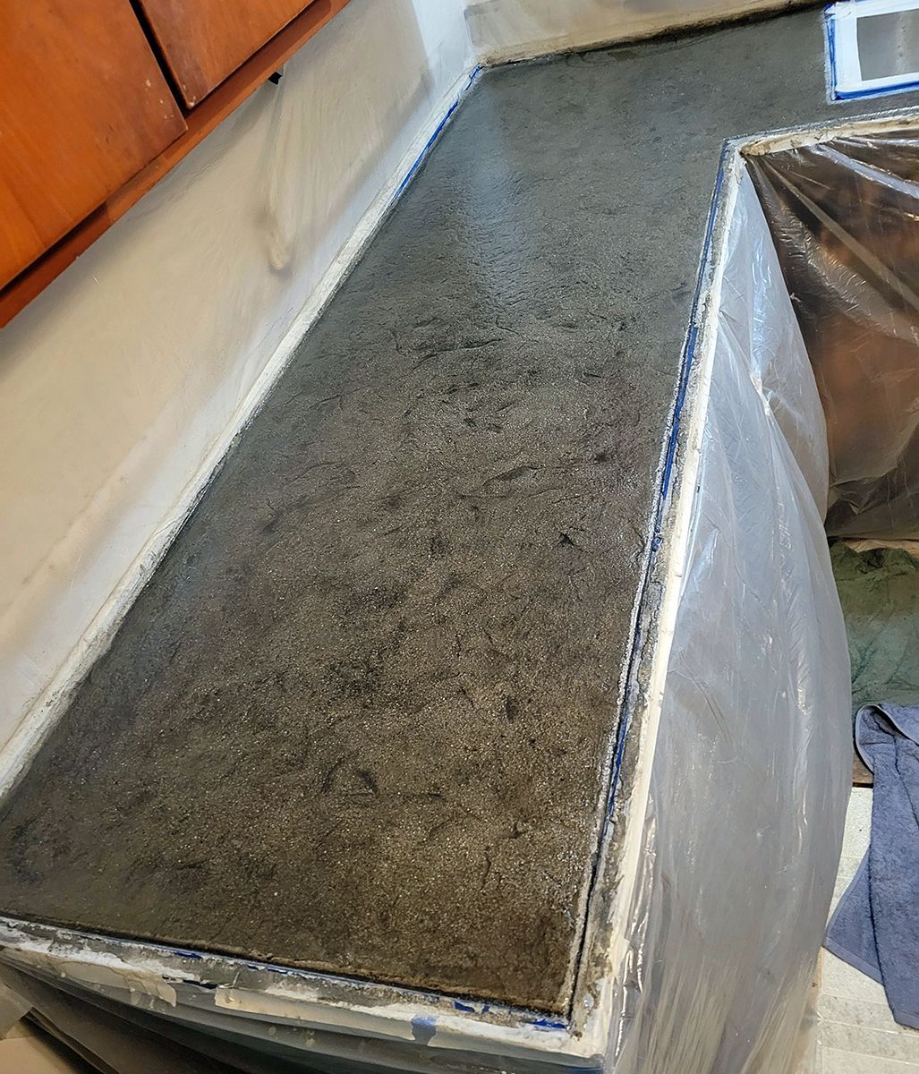 A black counter top is sitting in a kitchen next to a sink.