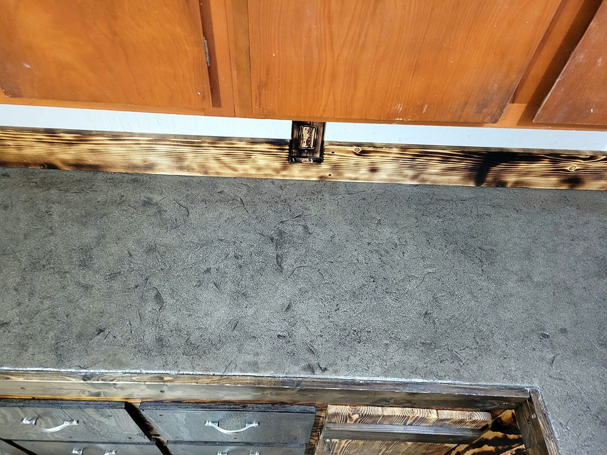 A kitchen counter with a wooden frame and a gray counter top.