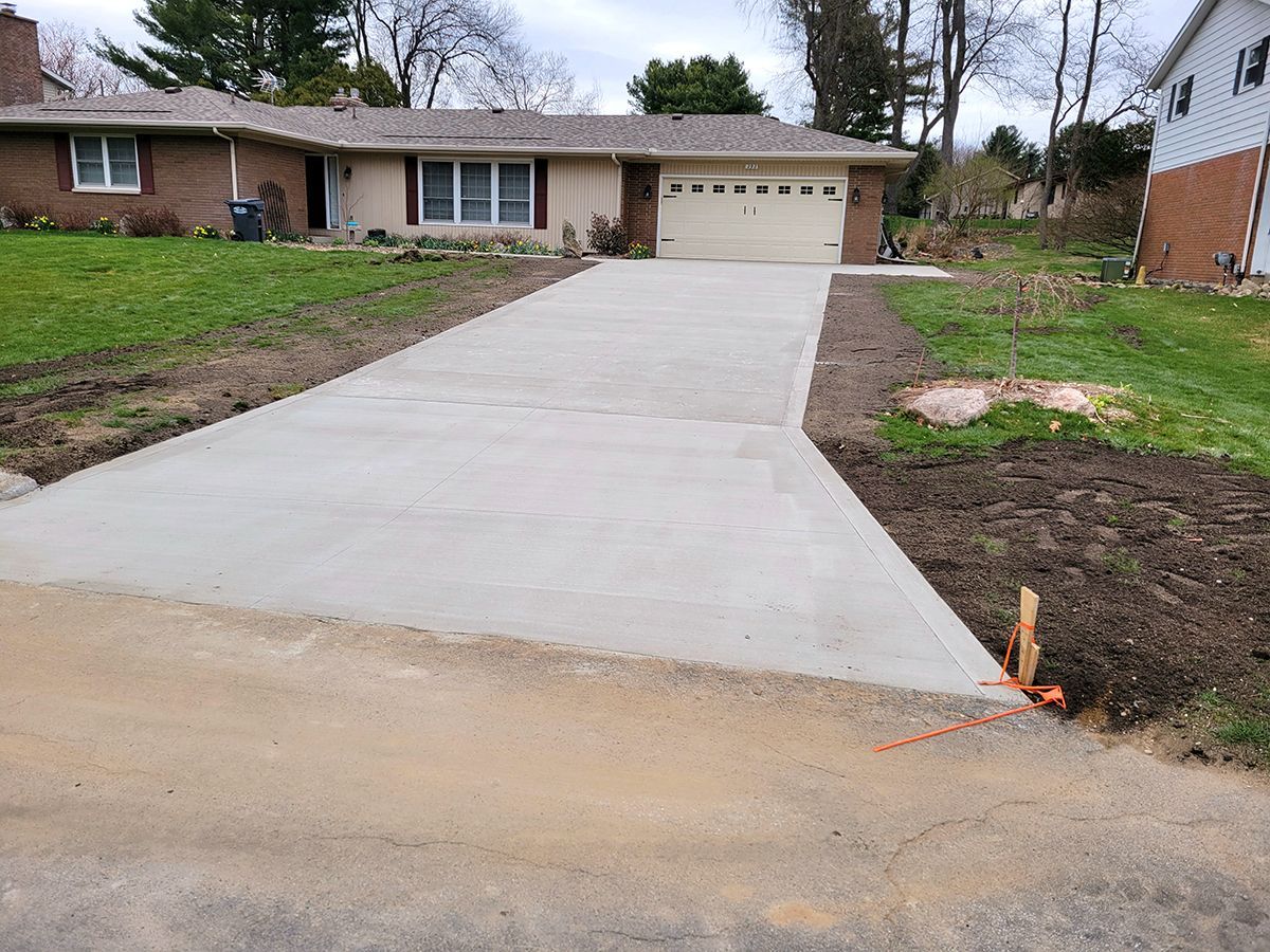 A concrete driveway is being built in front of a house.