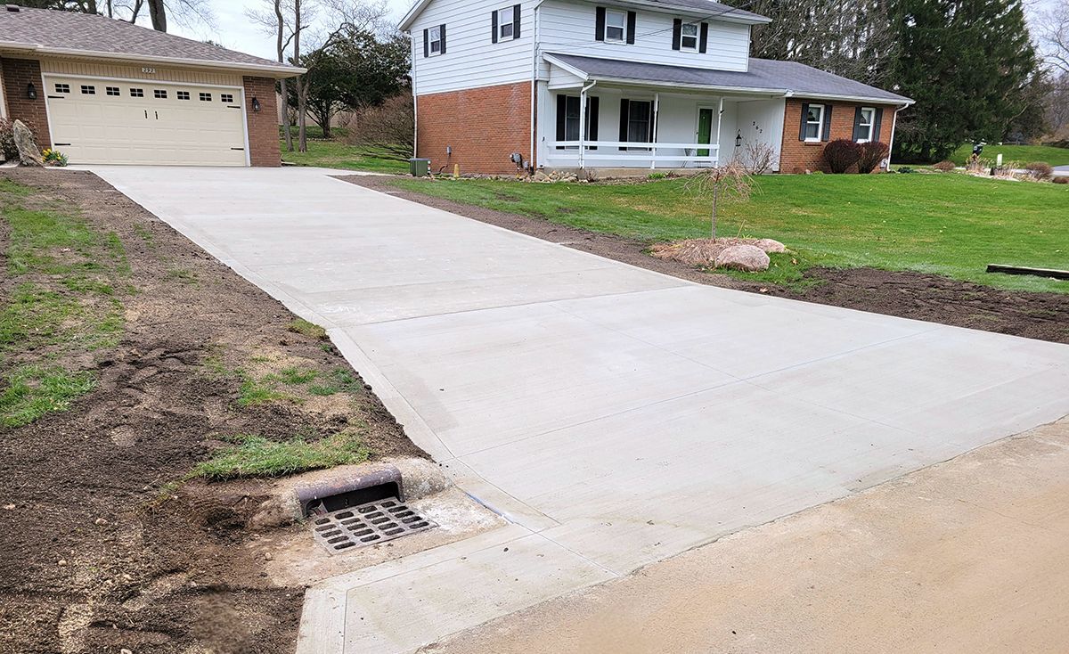 A concrete driveway leading to a house with a garage.