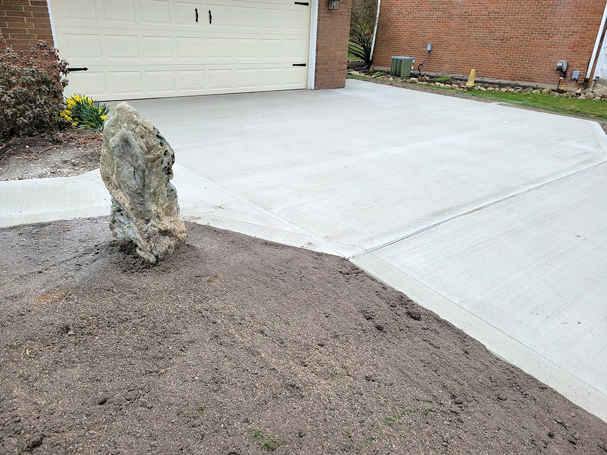 There is a large rock in the middle of the driveway.
