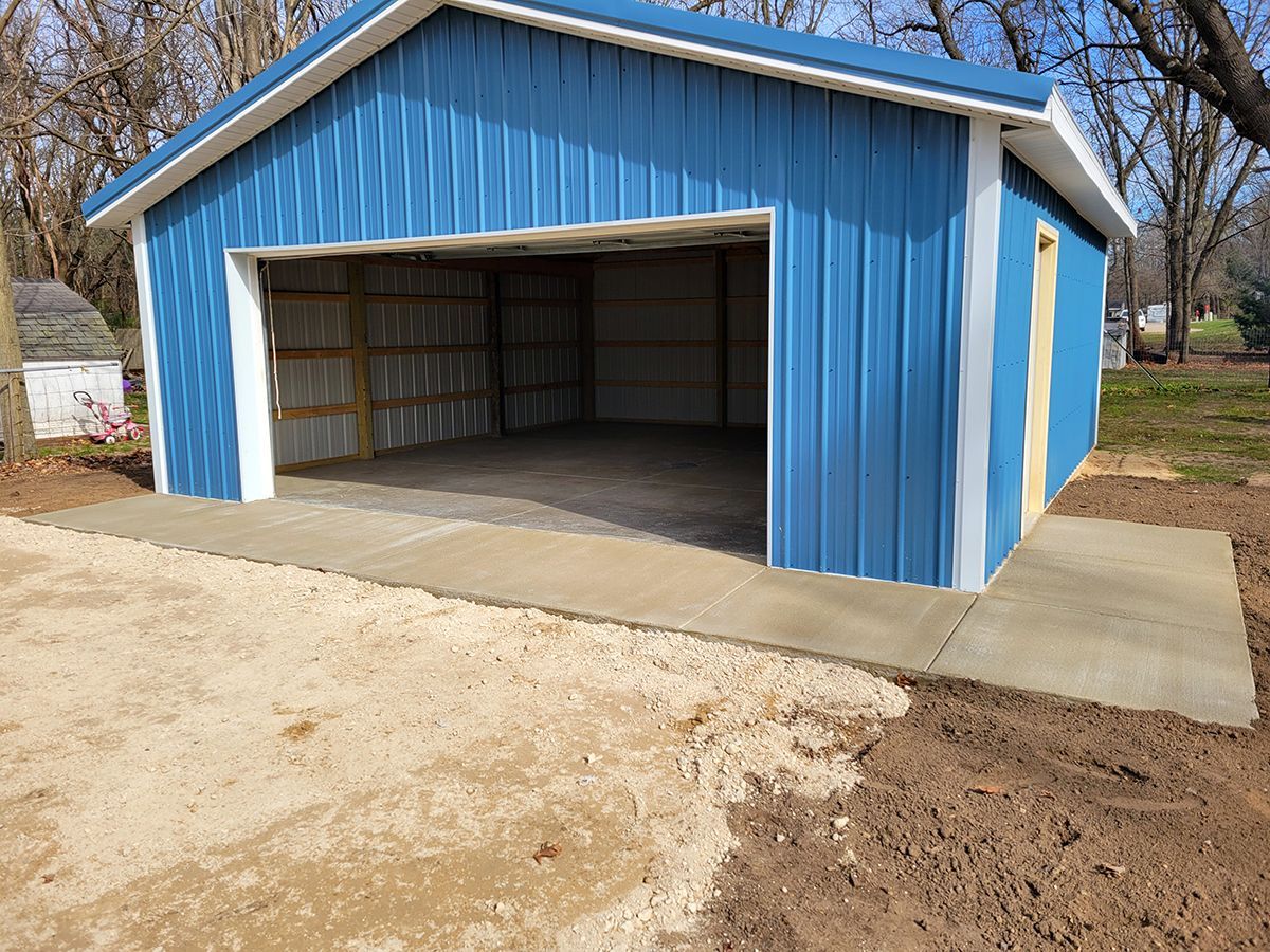 A blue and white garage with a concrete walkway leading to it.