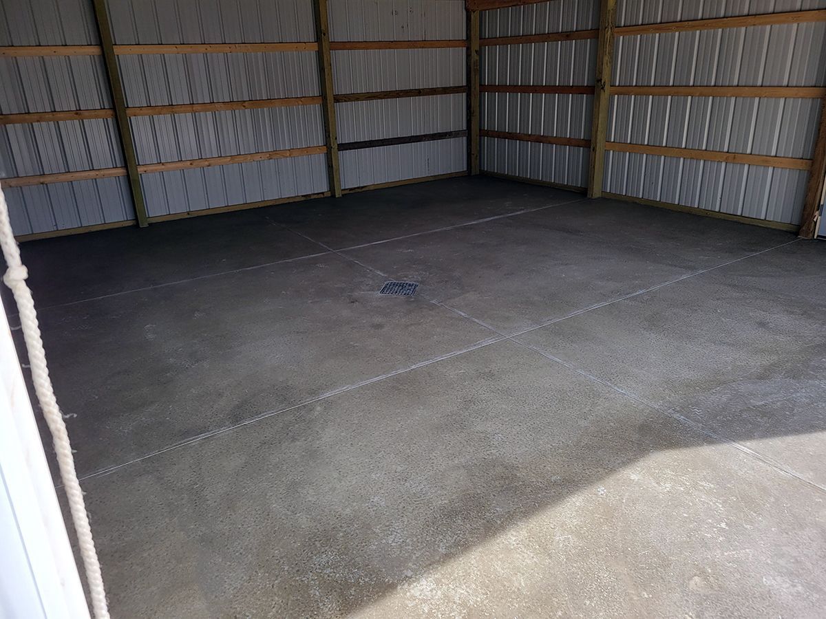 An empty garage with a concrete floor and wooden walls