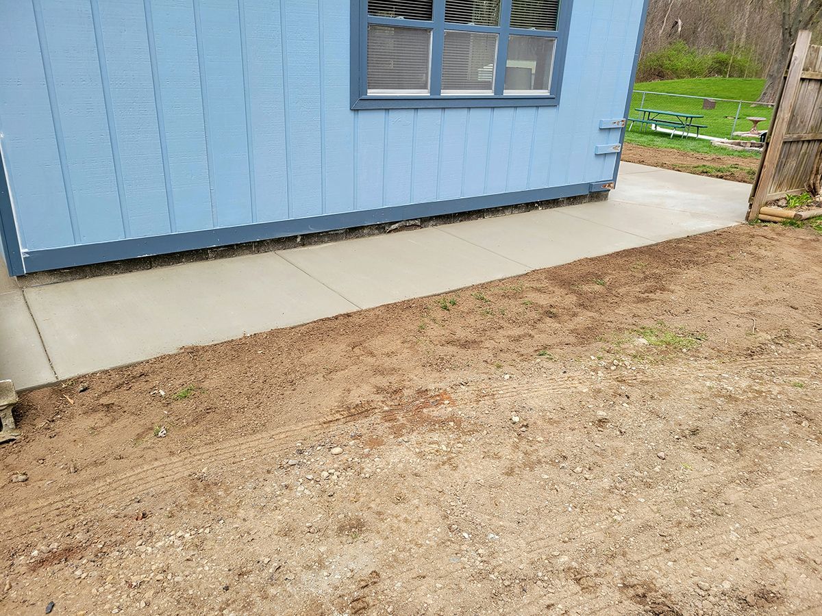 A blue house with a concrete walkway leading to it.