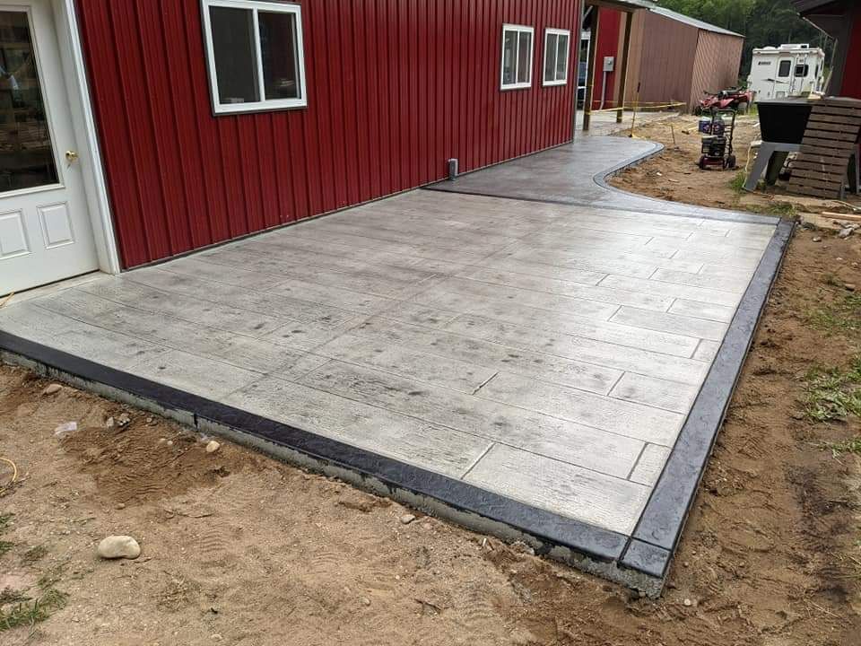 A concrete patio is being built in front of a red barn.