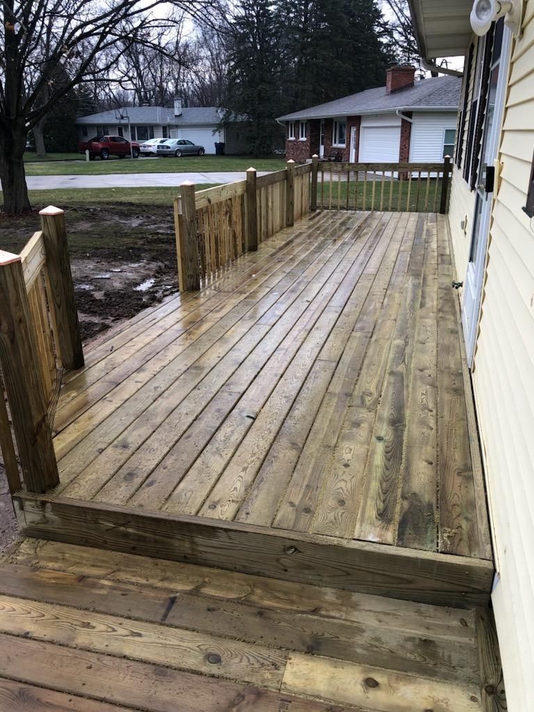 A wooden deck is sitting on the side of a house.