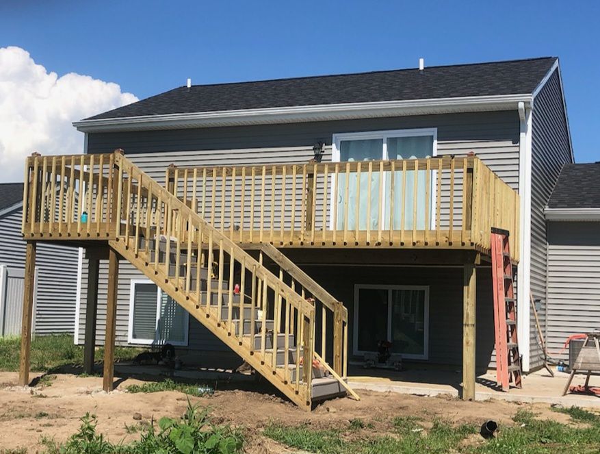 A house with a wooden deck and stairs in front of it.