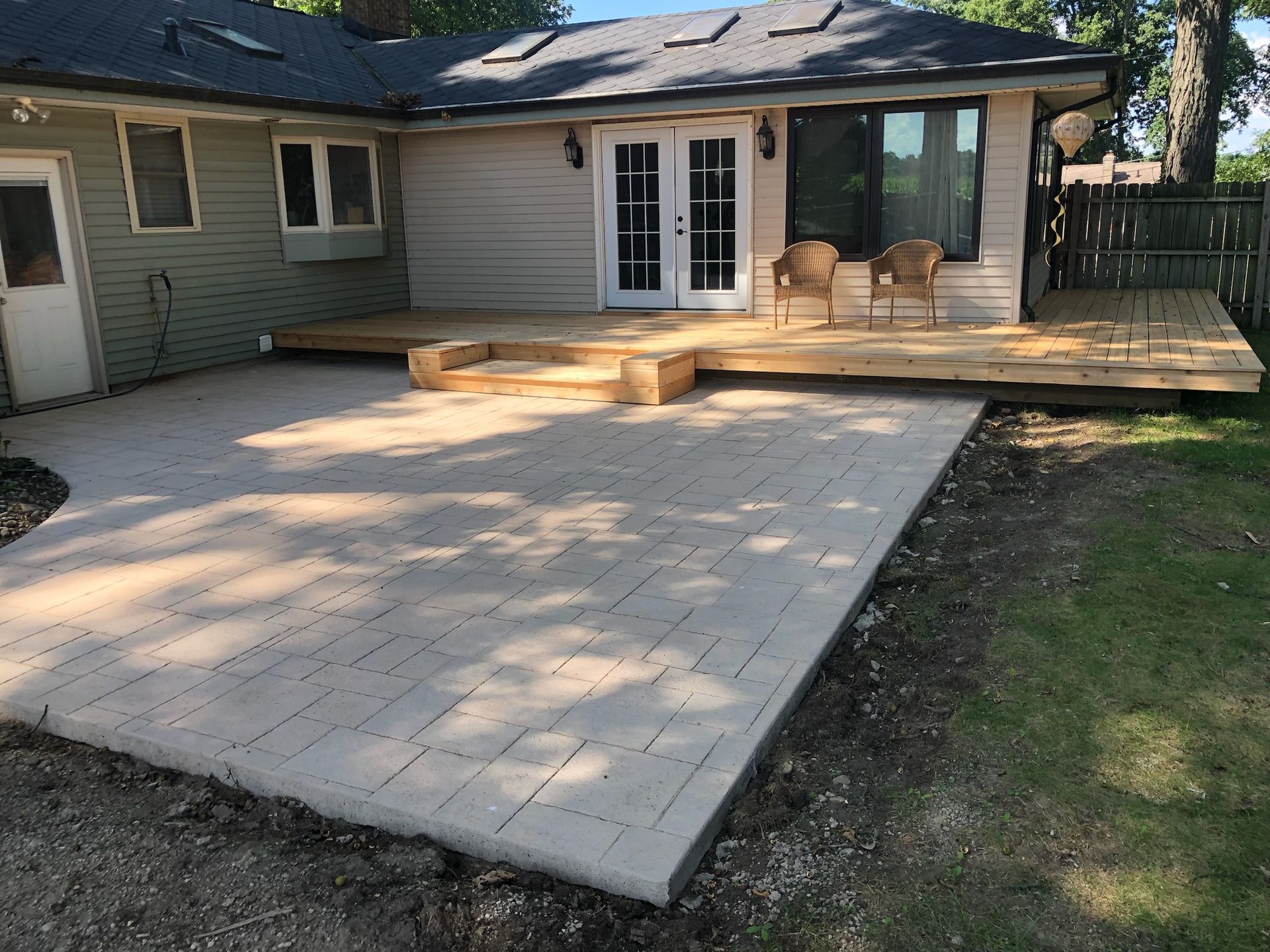 A house with a wooden deck and chairs in front of it.