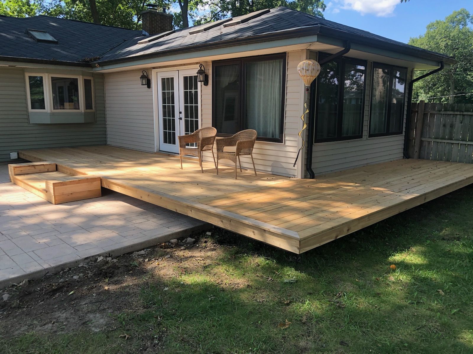 A house with a wooden deck and chairs in front of it.