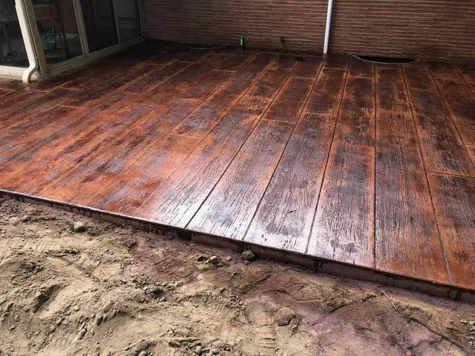 A patio with a wooden floor and a brick wall.