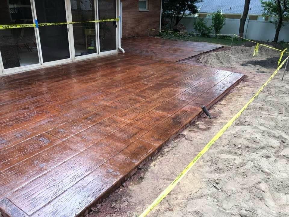 A concrete deck is being built in the backyard of a house.