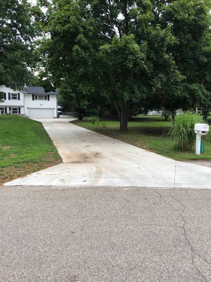 A concrete driveway leading to a house with a mailbox on the side of it.