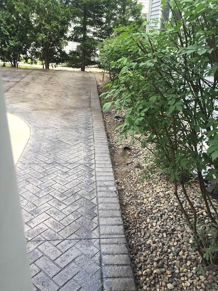 A brick walkway surrounded by trees and gravel in a park.