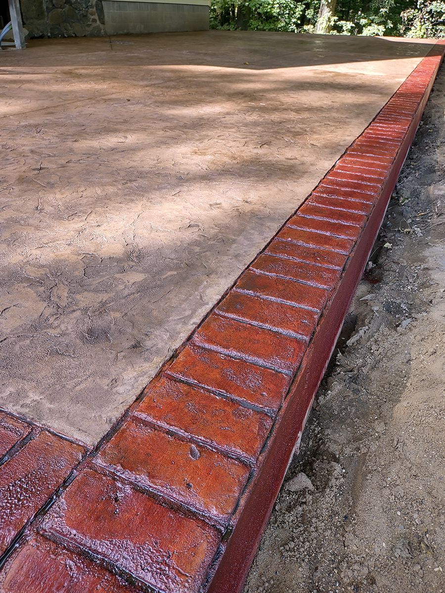 A close up of a brick border on a concrete driveway.