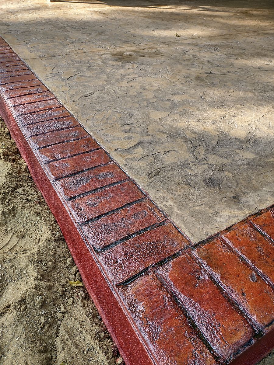 A close up of a brick border on a concrete driveway.