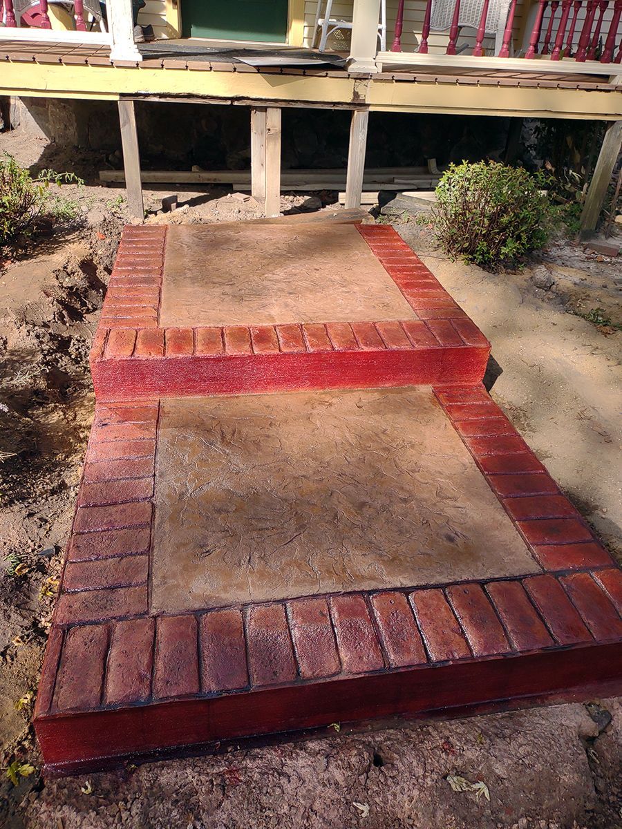 A concrete walkway with brick steps leading up to a porch.