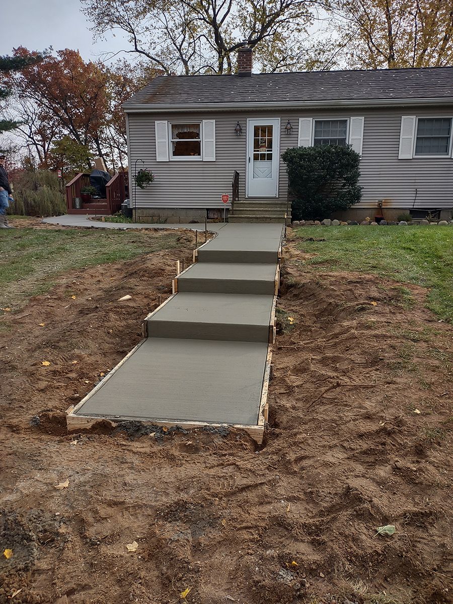 A concrete walkway is being built in front of a house.