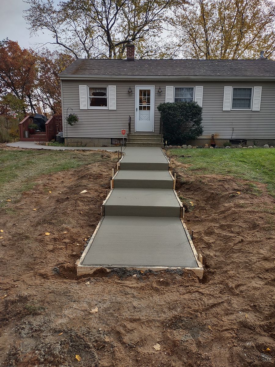 A concrete walkway is being built in front of a house.