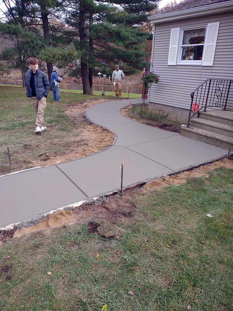 A concrete walkway is being built in front of a house.