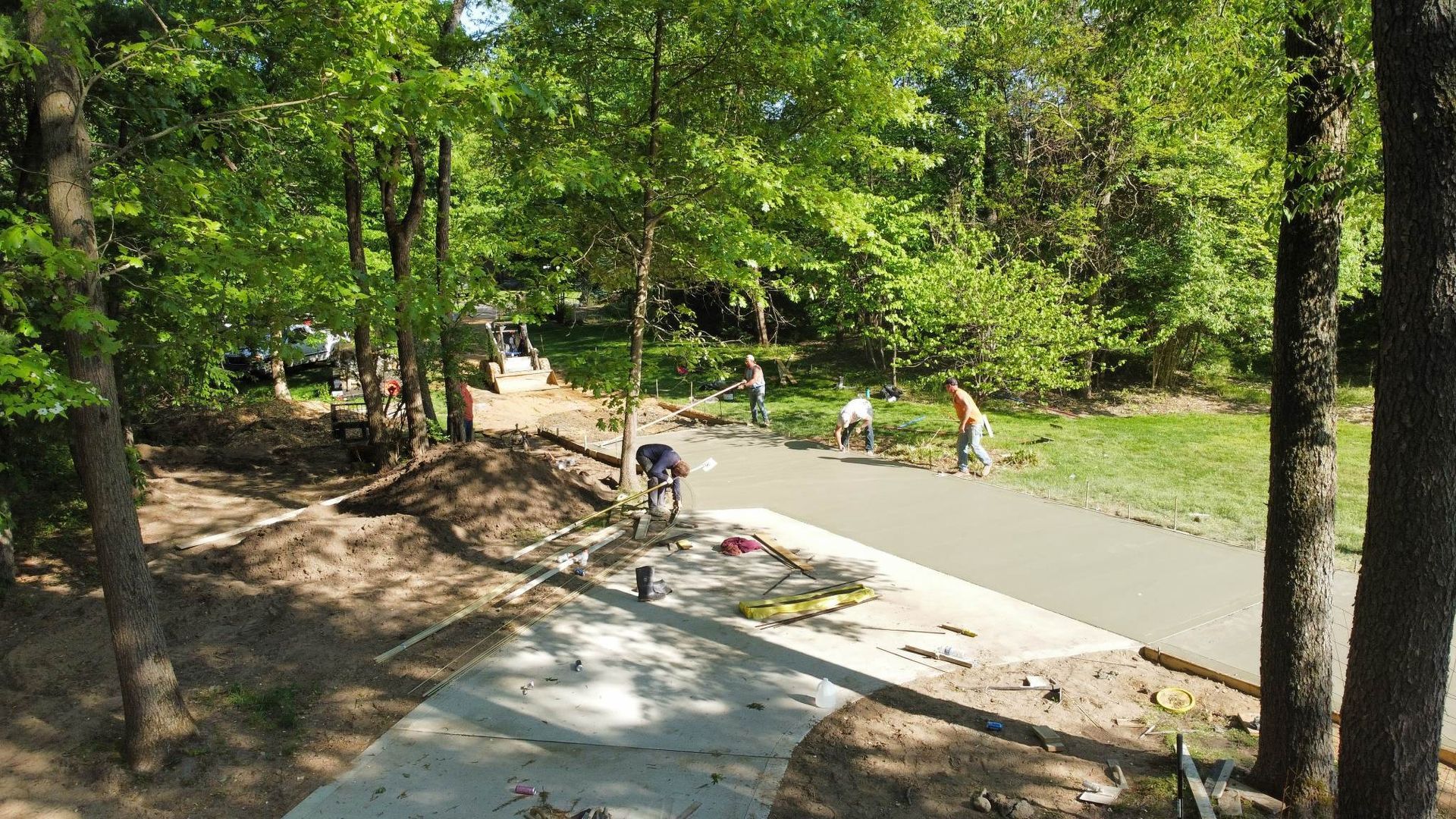 A group of people are working on a sidewalk in the woods.