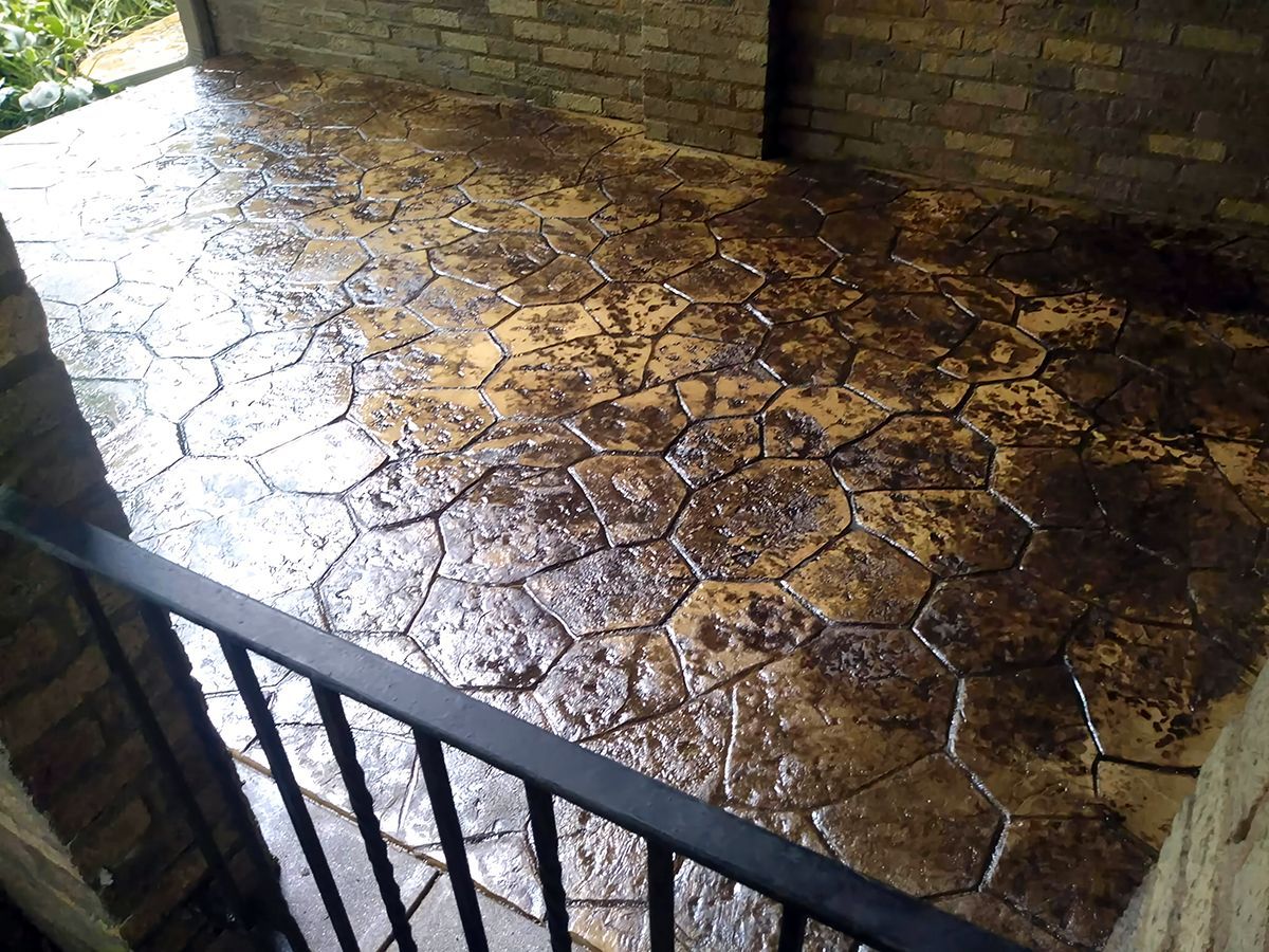 A patio with a metal railing and a brick wall behind it.