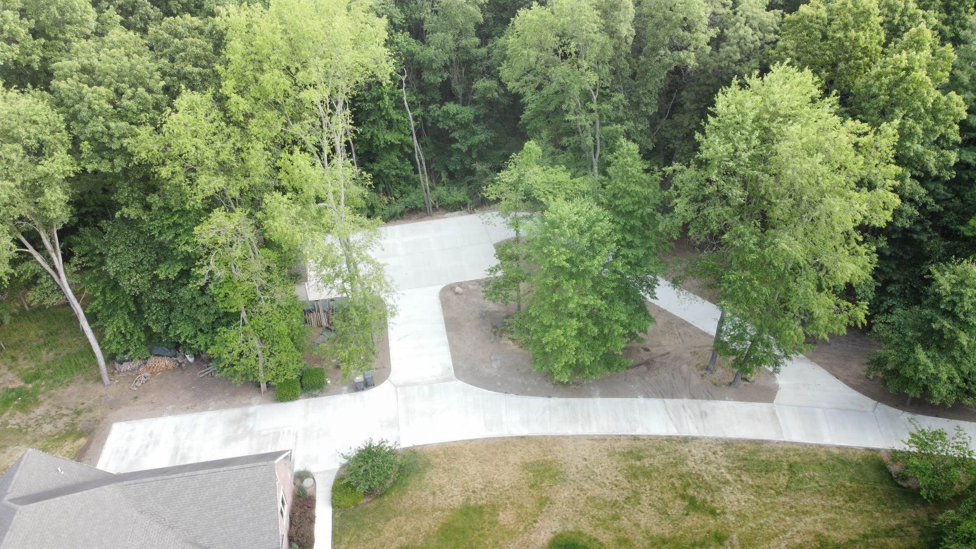 An aerial view of a concrete driveway surrounded by trees.