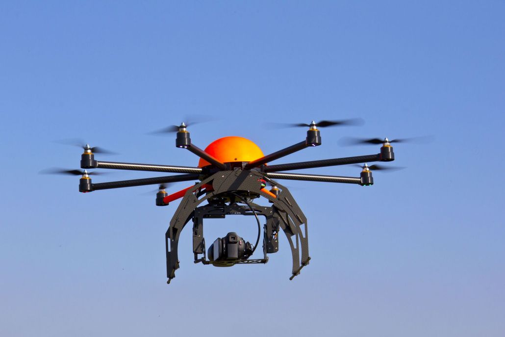 Orange drone flying against a blue sky