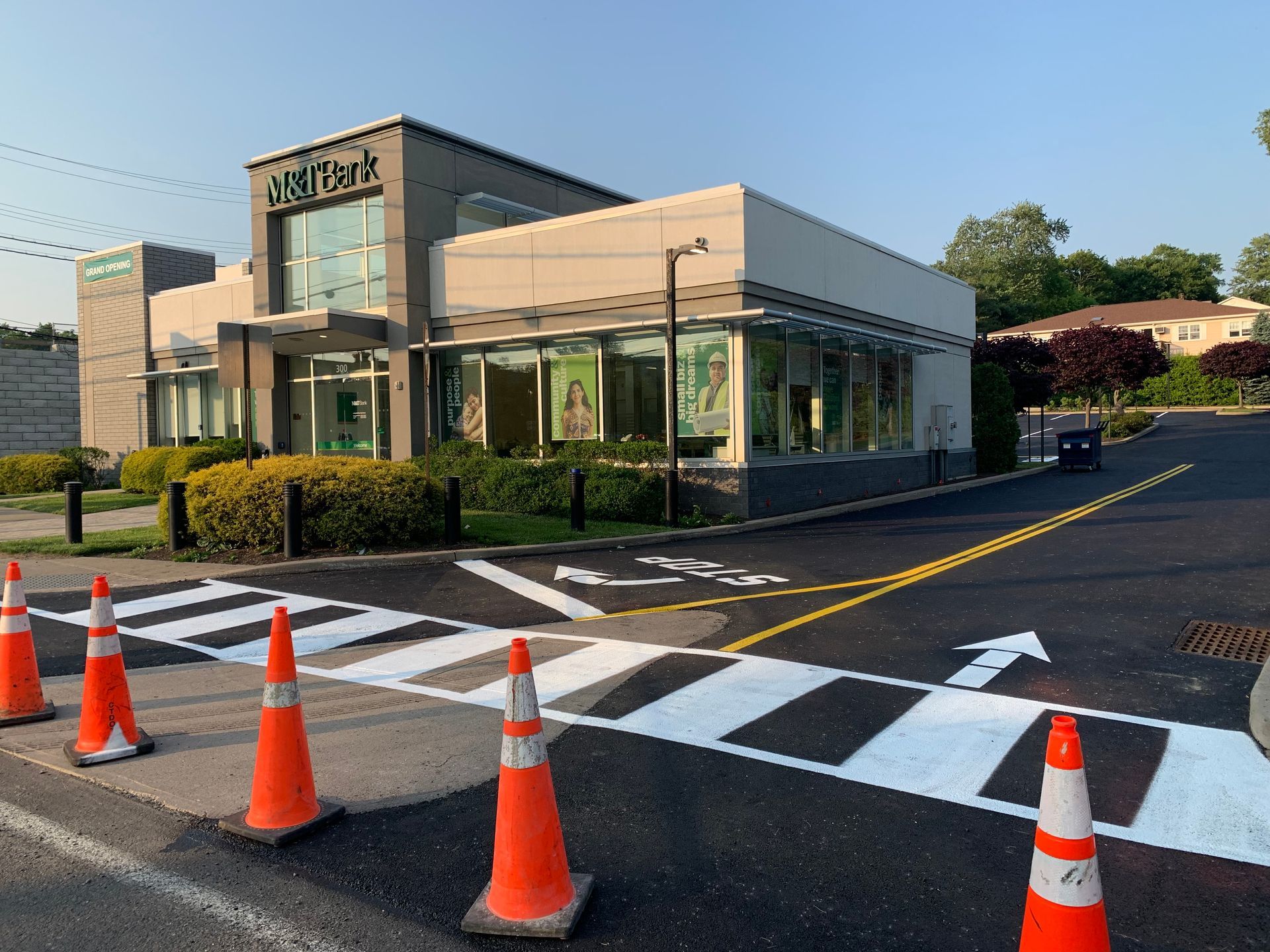 Modern restaurant building with a drive-through lane, traffic cones, and a crosswalk at dusk