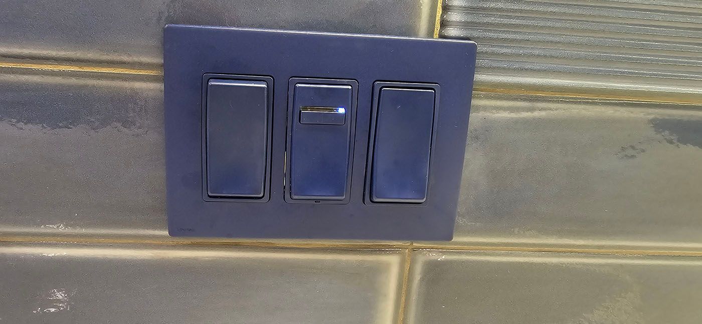A close up of a light switch on a tiled wall