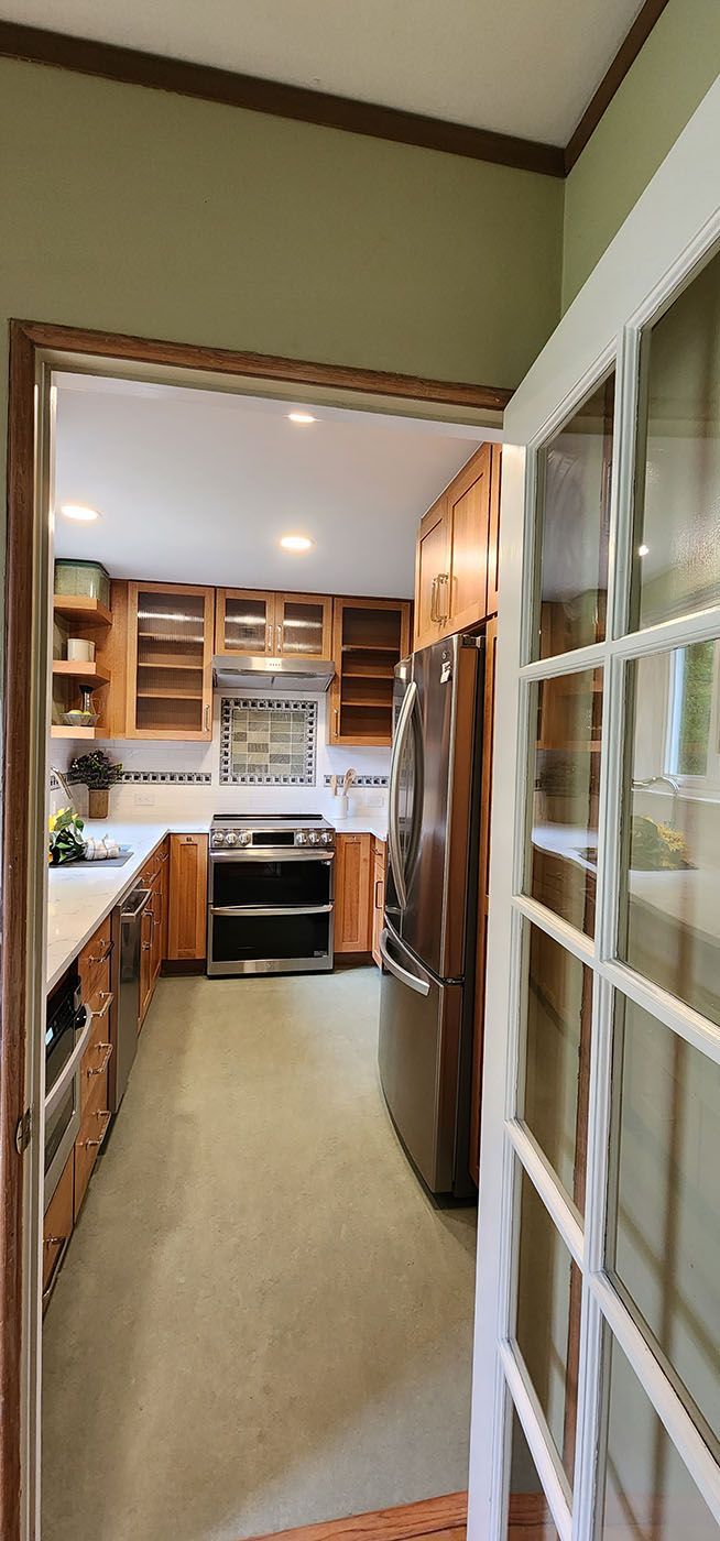 A kitchen with a refrigerator, stove, sink, and cabinets