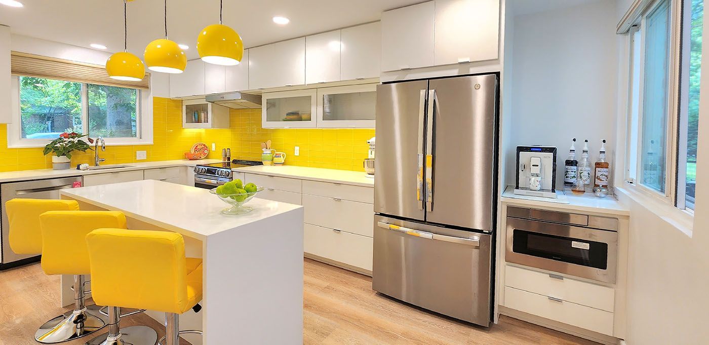 A kitchen with yellow cabinets, stainless steel appliances, and yellow chairs